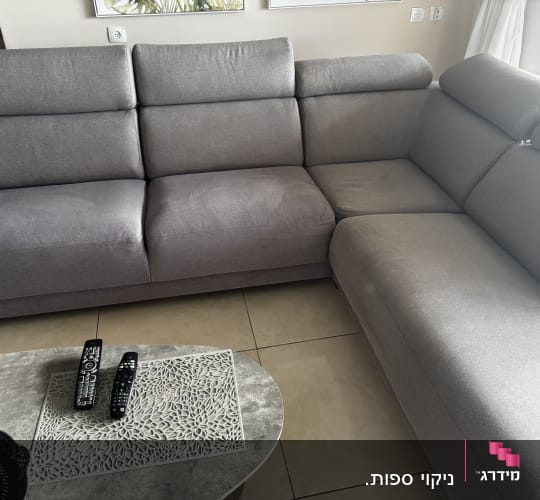 ספה אפורה עם שלט רחוק על שולחן